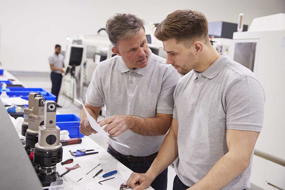 engineer-and-apprentice-discussing-job-sheet-in-fa-2021-04-02-20-00-49-utc